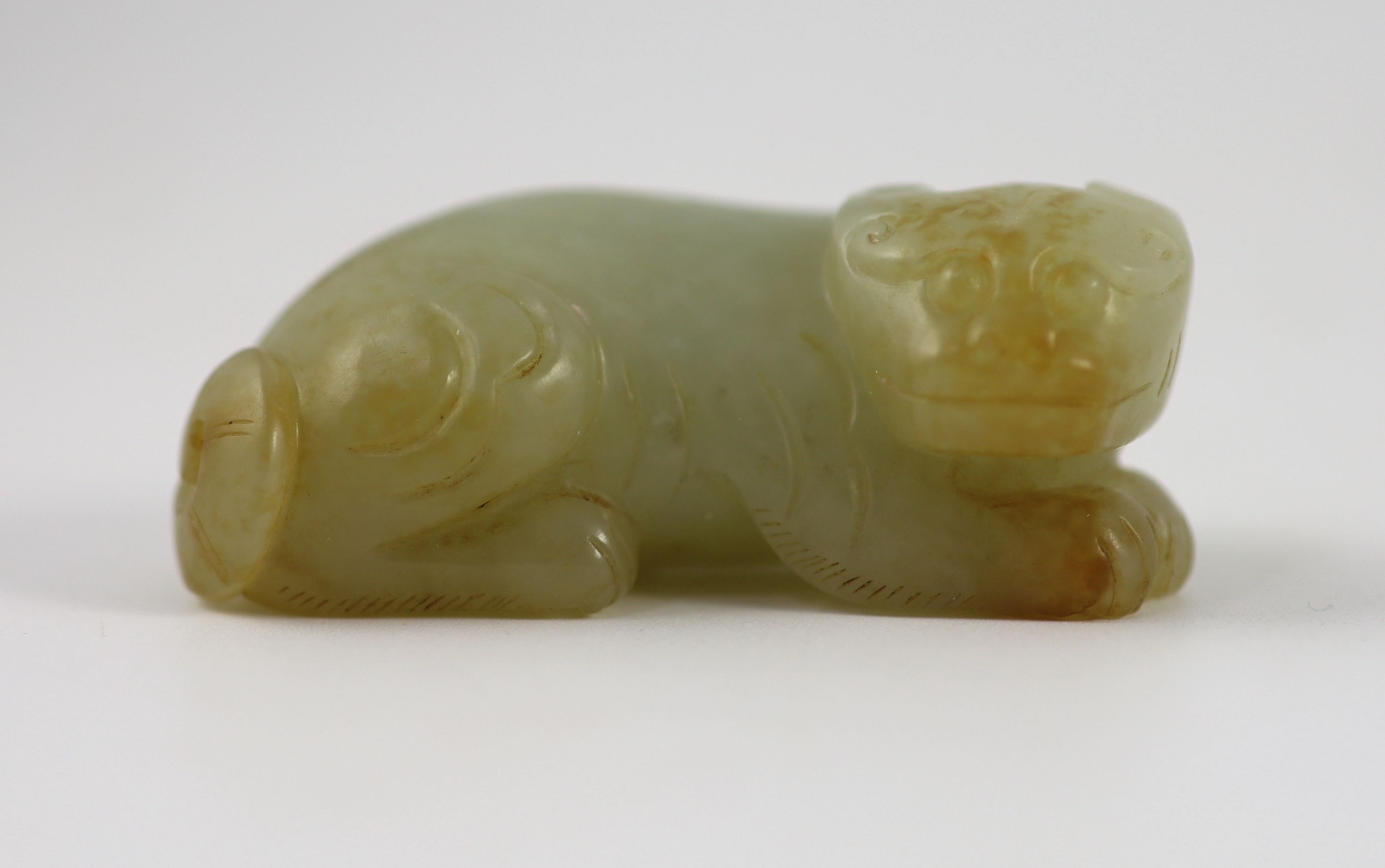 A Chinese pale celadon and russet jade figure of a lion dog, 6.2 cm long